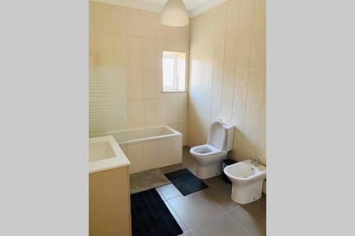 a bathroom with a toilet and a tub and a sink at Beach House (Leirosa) in Figueira da Foz