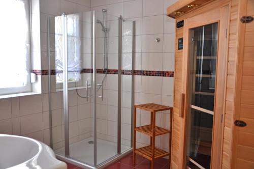 uma casa de banho com uma cabina de duche em vidro e um banco de madeira em Ferienhaus Müritzsonne / EG-Appartement em Marienfelde