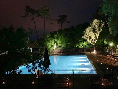 einen Swimmingpool in der Nacht mit Sonnenschirm und Stühlen in der Unterkunft Green Resort in Ondres