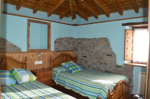 a bedroom with two beds and a stone wall at Casa el Fanoso in Luarca