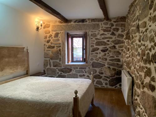 a bedroom with a bed and a stone wall at Casa D'Campo Ferreira in Pitões das Júnias