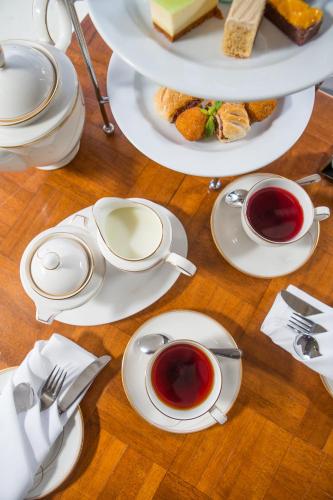 a table with plates of food and cups of tea at James Cook Hotel Grand Chancellor in Wellington