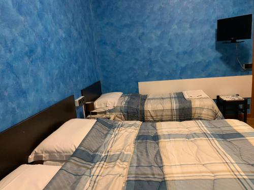 two beds in a bedroom with blue walls at Casa Vacanza Nadia in Bergamo