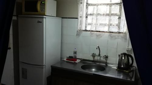 una pequeña cocina con fregadero y nevera. en Los Abuelos, en La Coronilla