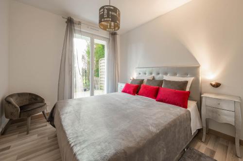 a bedroom with a large bed with red pillows at EDEN PARK LUXE DISNEY in Montévrain