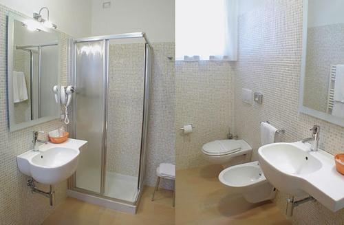 a bathroom with two sinks and a shower and a toilet at Hotel Miami in Civitella del Tronto