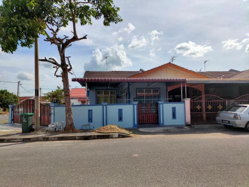 a blue house with a car parked in front of it at Homestay Tengku Maheran in Jitra