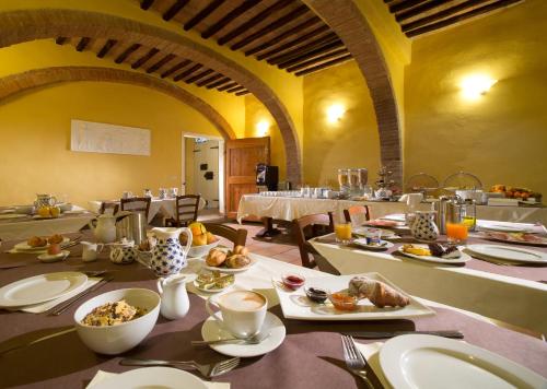 une salle à manger avec une table et des assiettes de nourriture dans l'établissement Hotel Palazzo di Valli, à Sienne