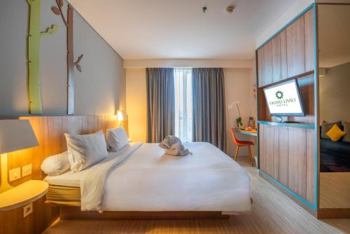 a hotel room with a large bed and a desk at Grand Livio Kuta Hotel in Legian