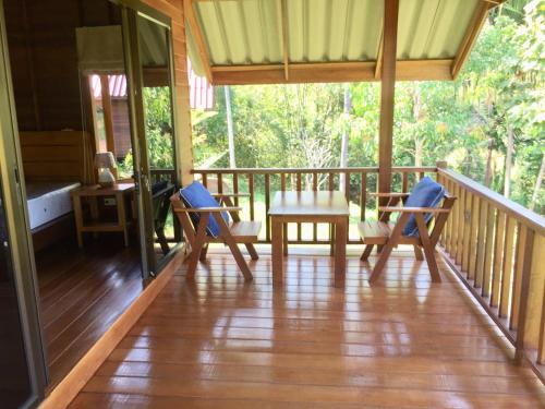 a porch of a house with a table and chairs at Sabai House Bungalow in Ko Yao Noi