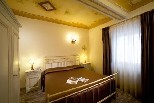 a bedroom with a bed and two night stands and a window at Hotel Palazzo di Valli in Siena