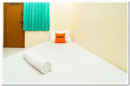 a bed with an orange pillow on top of it at Koolkost Near Universitas Maranatha 2 Bandung - Minimum Stay 30 Nights in Bandung