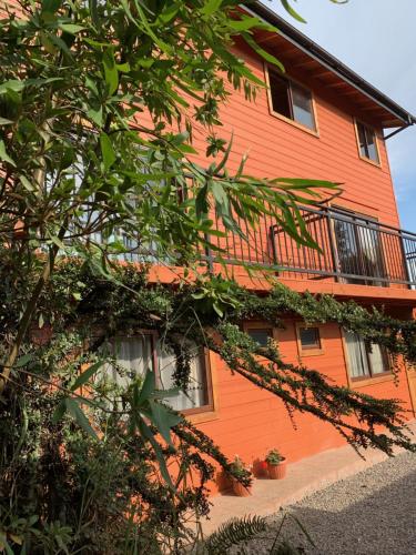 an orange building with a balcony on the side of it at cabañas los Ulmos in Licán Ray