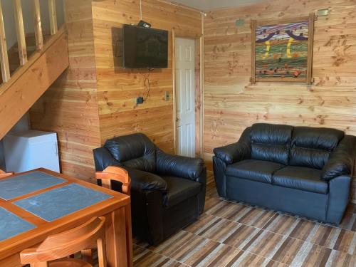 a living room with two leather couches and a television at cabañas los Ulmos in Licán Ray