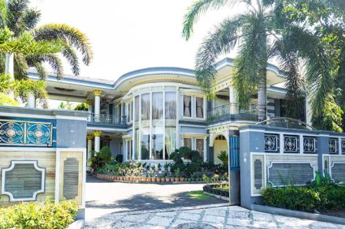 a large house with palm trees in front of it at RedDoorz Premium @ Sea Residence Manado in Manado