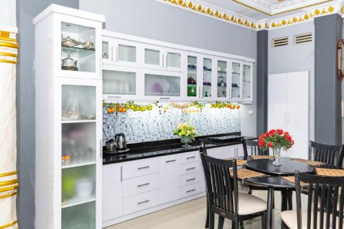 a kitchen with white cabinets and a table and chairs at RedDoorz Premium @ Sea Residence Manado in Manado