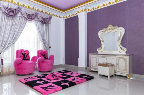 a living room with pink chairs and a mirror at RedDoorz Premium @ Sea Residence Manado in Manado