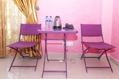 two purple chairs and a table with a tea kettle on it at RedDoorz Premium @ Sea Residence Manado in Manado