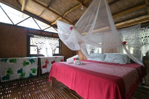 a bedroom with a bed with a mosquito net at Busuanga Backpackers in Concepcion