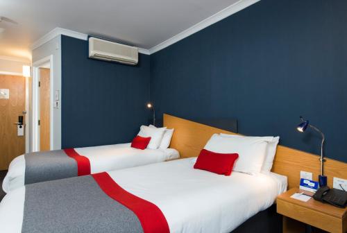 two beds in a room with blue walls and red pillows at Holiday Inn Express Birmingham Oldbury by IHG in Oldbury