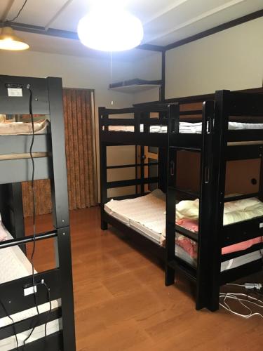 Habitación con 3 literas y lámpara. en Kakunodate Guesthouse Fuga en Senboku