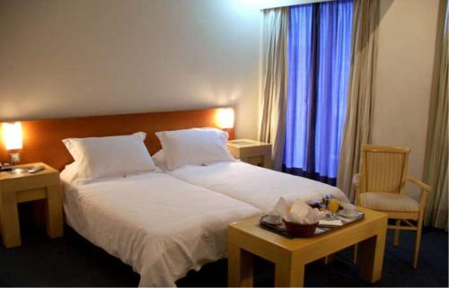 a bedroom with a large white bed and two tables at Dorian Inn - Sure Hotel Collection by Best Western in Athens
