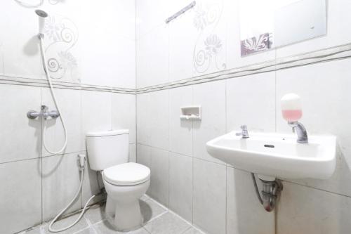 a white bathroom with a toilet and a sink at Hotel Gani in Jakarta