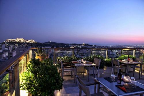 a restaurant with tables and chairs on a balcony at night at Dorian Inn - Sure Hotel Collection by Best Western in Athens