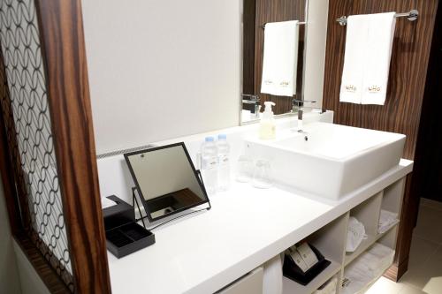 a bathroom with a white sink and a mirror at Hotel Gracery Seoul in Seoul