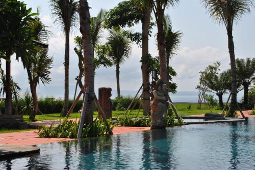 a person on a swing in a pool with palm trees at Kori Maharani Villas & Resort in Keramas