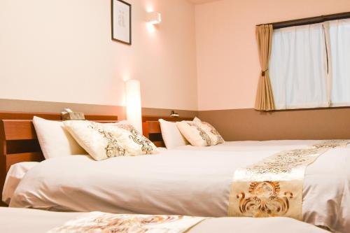 a hotel room with two beds and a window at Guest House One More Heart Kyoto Station South 1 in Kyoto
