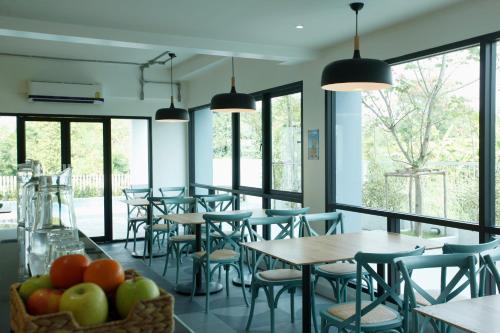 a dining room with tables and chairs and windows at Port Canary Airport Hotel in Lat Krabang