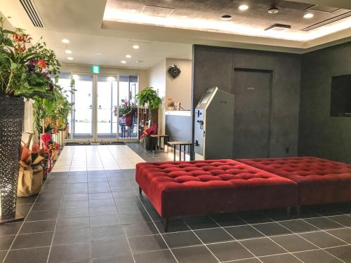 um quarto com um banco vermelho num edifício em Hotel Livemax Toyama em Toyama