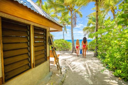 two women walking towards a house on the beach at Barefoot Manta Island Resort in Drawaqa Island