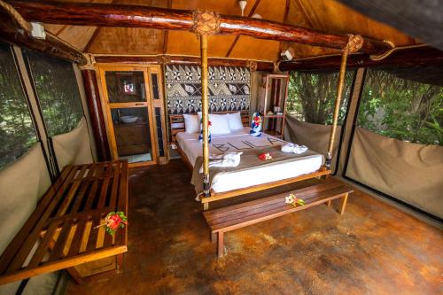 a bedroom in a tent with a bed and a bench at Barefoot Manta Island Resort in Drawaqa Island