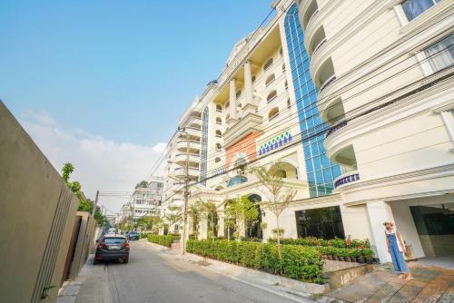 a woman standing on a street in front of a building at Romance Hotel Sukhumvit 97 in Bangkok