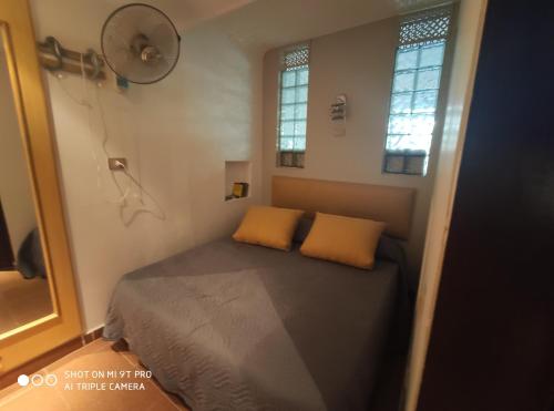 a small bedroom with a bed and two yellow pillows at sharm suite privata Domina in Sharm El Sheikh