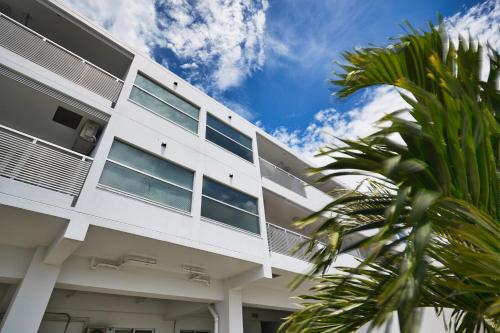 a white building with a palm tree in front of it at FreedomHillsフリーダムヒルズA棟 in Tomigusuku