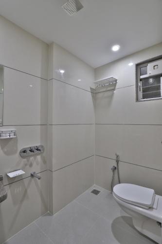 a white bathroom with a toilet and a window at HOTEL LE GRAND in Surat