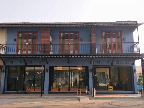 a blue building with windows and a balcony at Baan Khun Nine in Ratchaburi