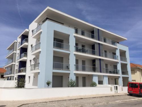 a white apartment building with a red bus in front of it at Beautiful Apartment in S o Martinho do Porto with Balcony in São Martinho do Porto