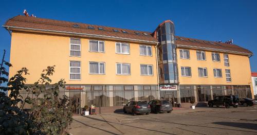 a large building with cars parked in front of it at Hotel Dana in Satu Mare