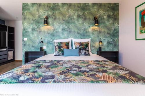 第戎的住宿－Le Clos des Jardins，一间卧室配有一张带热带壁纸的床