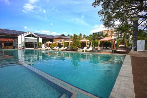 a large swimming pool with chairs and umbrellas at Queenco Hotel & Casino in Sihanoukville