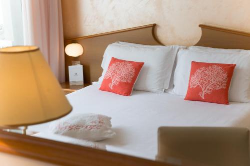 a bed with red pillows and a laptop on it at Corallo Wellness Hotel in Diano Marina