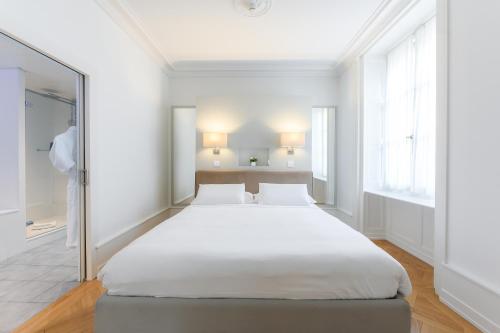 a large bed in a white room with a mirror at Swiss Luxury Apartments in Geneva