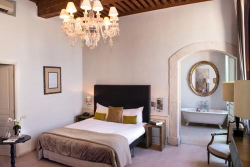 - une chambre avec un lit, une baignoire et un lustre dans l'établissement Château De Massillan, à Uchaux