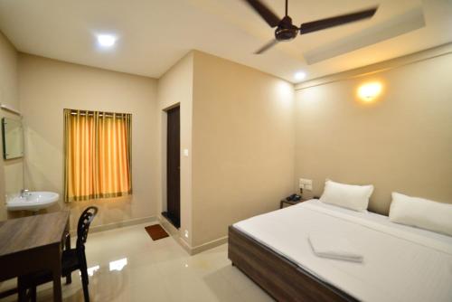 a bedroom with a bed and a desk and a sink at Hotel Priya in Kottakkal