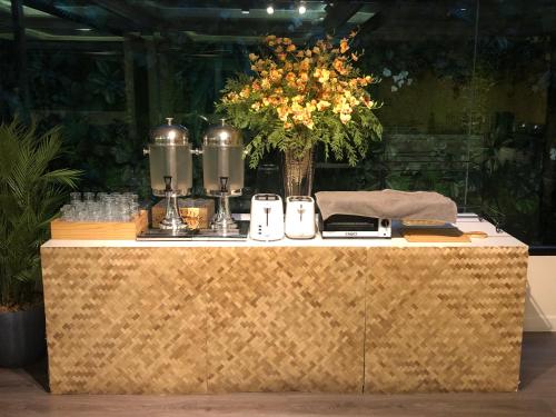 a table with a vase of flowers on top of it at Romance Hotel Sukhumvit 97 in Bangkok