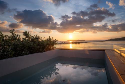 a swimming pool with the sunset in the background at Shapes Luxury Suites in Ermoupoli